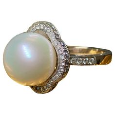 An elegant and timeless ring done in 18K white gold centered by a cream colored 13.4mm large South Sea pearl with very minor pitting and a beautiful, even luster. Bead set around the pearl and on the shoulders of the ring is .73cttw in perfectly matched G-H color Vs1-2 clarity round diamonds. A very solid and well made piece. Dimensions/Weight: Ring measures .75” in diameter and weighs 10.3g. Size 7 (sizable). Condition: All stones are secure and in perfectly wearable condition. Pearl is undamag Luxury Timeless Pearl Ring With Round Cut, Timeless Ring, Diamond Cocktail Ring, Color Crema, Diamond Cocktail Rings, Sea Pearl, Bead Set, South Seas, South Sea Pearls