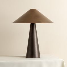 a lamp sitting on top of a table next to a white cloth covered tablecloth