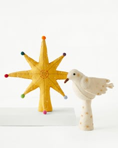 a white bird standing next to a yellow star ornament on top of a table