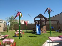 an outdoor play area with toys and picnic tables in the back yard on a sunny day