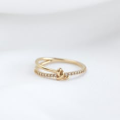 a gold ring with two small diamonds on the side and a knot in the middle