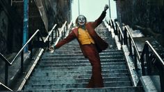 the joker is coming down the stairs with his arms in the air