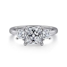 a three stone princess cut diamond ring with four diamonds on the band and sidestones