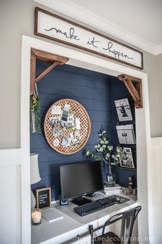 a desk with a computer on it in front of a blue wall and some pictures