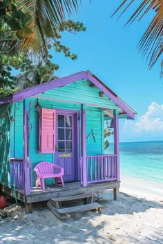 a purple and blue house sitting on top of a sandy beach