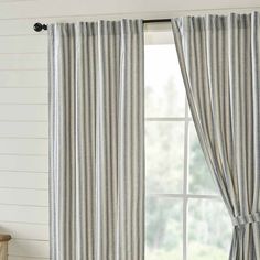 a window with striped curtains in front of it and a wooden table next to it