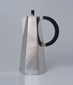 a silver and black coffee pot sitting on top of a table