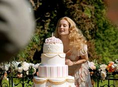 a woman standing in front of a wedding cake