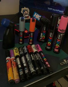 many different types of pens and lighters on a table with a television in the background