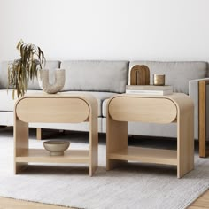 two wooden tables sitting on top of a white rug in front of a gray couch