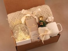 a christmas gift box is packed with items such as mugs, cookies and candles