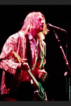 a man standing in front of a microphone holding a guitar