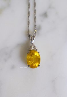 Metal: 14kt White Gold Stone: Yellow Sapphire And Diamond Stone Shapes: Round And Oval-Shape Yellow Sapphire Weight: 3.27 ctw, 9.84 x 7.82 mm Diamond Weight: .08 ctw, round diamonds Measurements Of Pendant From Bail To Bottom Of Pendant: 19.93 mm Weight of entire piece with chain: 2.50 grams Type of Chain: 1.2mm Diamond-cut Singapore Chain Length of Chain: 16 Inches Type of Lock: Spring Ring Note: Other chain styles and lengths available. Pendant can also be sold without chain. Please inquire if Gia Certified Oval Gemstones For Fine Jewelry, Oval Fine Jewelry Necklace With Accent Stones, Oval Necklace With Accent Stones, Gia Certified Oval Cabochon Jewelry Gift, Oval Necklace With Accent Stones In Fine Jewelry Style, White Gold Oval Gemstones Fine Jewelry, Oval Yellow Gold Gemstones Fine Jewelry, Yellow Gold Oval Gemstones Fine Jewelry, Oval Yellow Gold Gemstones With Accent Stones