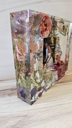 two vases sitting on top of a wooden table with flowers painted on the sides