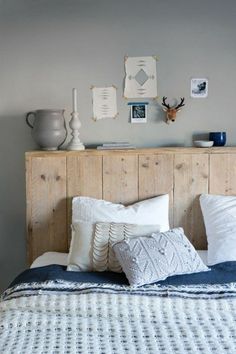 a bed with pillows and blankets on top of it next to a wooden headboard