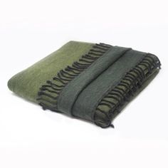 the green and black blanket is folded on top of each other, with fringes