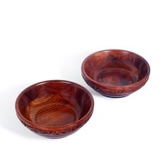 two wooden bowls sitting next to each other