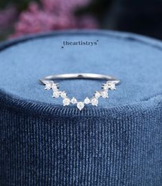 a close up of a ring on top of a blue velvet box with flowers in the background