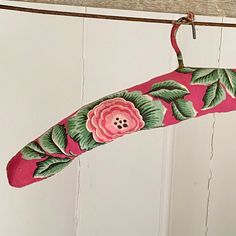 a pink umbrella with green leaves and flowers hanging from it's side on a clothes line