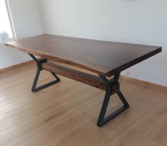 a wooden table sitting on top of a hard wood floor next to a clock mounted on the wall