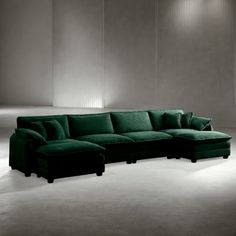 a large green couch sitting next to a white wall in a room with lights on