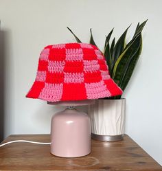 a crocheted hat sitting on top of a table next to a potted plant