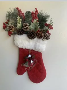 a christmas stocking hanging on the wall with pine cones and holly