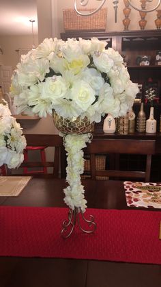 a vase with white flowers on a table in front of a red place mat and other items