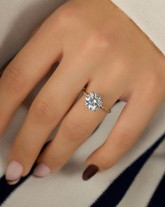 a woman's hand with a diamond ring on her left hand, and a striped sweater