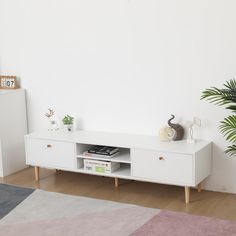 a living room with a white entertainment center and potted plant on the sideboard