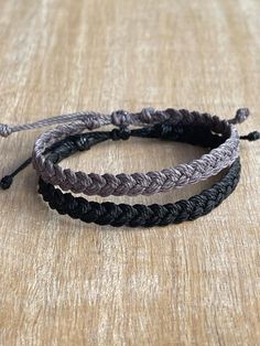 two braided bracelets sitting on top of a wooden table