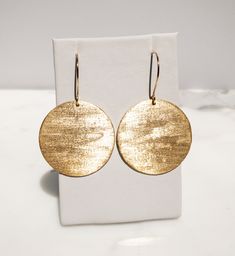 Are you looking for a unique and beautifully handcrafted accessory? Look no further than this handmade textured gold brass disc Earrings! As a single artisan handmade business based in California, I take pride in creating each pair of earrings with the utmost care and attention to detail. These earrings measure 2 inches long (including the ear wire) and 1.5 inches wide.  They are hand-textured for a unique look that makes them sparkle. They're made of solid brass.  The ear wires are also hand-made by me of 14k Gold-Fill. I believe in the quality of my work, which is why I offer a Happiness Guarantee. If for any reason you're not completely satisfied with your purchase, you can return it within 30 days for a full refund. These handmade textured gold brass circle disc earrings also make a wo Handmade 14k Gold Earrings For Everyday, Elegant Recycled Gold Earrings With Ear Wire, Gold Round Earrings For Everyday, Everyday 14k Gold Filled Earrings With French Hook, 14k Gold Circular Earrings, Adjustable Hammered 14k Gold Earrings, Everyday Handmade 14k Gold Earrings, Gold Recycled Gold Earrings With Ear Wire, Elegant Nickel Free Round Disc Earrings