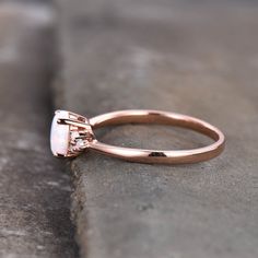 a close up of a diamond ring on a stone surface with the top setting in rose gold