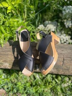 Astoria is a cross over sandal with open toe and an adjustable heel strap. The clog sandals come in black vegetable tanned leather and on mid natural soles. The vegetable tanned leather has a natural finish and should be kept away from water as it is sensitive to water stains but it will age with a beautiful rich patina. Heel height: 7 cm Platform height: 2.5 cm Fit: Narrow to medium width Leather Upper: Portuguese pull up leather Wood: Varnished lime wood Footbed: Natural wood for excellent moi Black Slingback Mules With Rubber Sole, Black Closed Toe Slingback Sandals With Stacked Heel, Black Slingback Sandals With Wooden Heel, Black Slingback Sandals With High Wooden Heel, Black Slingback Sandals With Wooden Heel And Round Toe, Black Summer Clogs With Wooden Heel, Black Clogs With Wooden Heel For Summer, Slingback Black Clogs With Buckle Closure, Black Clogs With Heel Strap And Block Heel