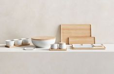 a white table topped with bowls and chopsticks next to a wooden cutting board