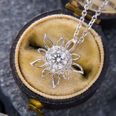 This sweet floral pendant is centered with one (1) round brilliant cut diamond, weighing 0.50 carats, set in four prongs. The diamond is surrounded by a halo of sixteen (16) round brilliant cut diamonds in shared prong settings. The pendant measures 15.0mm wide by 4.0mm thick and is signed JD & CO. The pendant hangs from a 1.3mm wide diamond cut adjustable cable chain that is 18 inches long and can be worn at 16 or 17 inches.  The chain is finished with a lobster clasp. Diamond White Flower-shaped Diamond Jewelry, Diamond White Diamond Flower-shaped Jewelry, Moissanite Diamond Necklace In White Gold With Halo Setting, Diamond White Flower-shaped Jewelry With Halo Design, White Gold Flower Pendant With Brilliant Cut, Moissanite Diamond Necklace With Halo Design, White Gold Brilliant Cut Flower Pendant, Dazzling Moissanite Halo Diamond Necklace, Elegant Flower Shaped Jewelry With Halo Setting