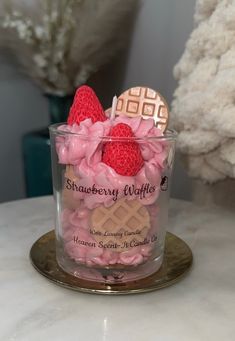 strawberries and waffles in a glass container on a table next to some flowers