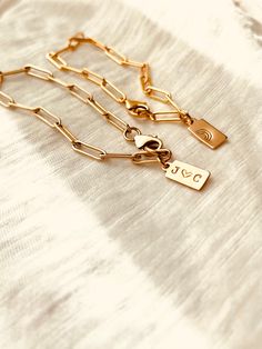 This stylish and straightforward Custom Tag Paperclip Bracelet is expertly crafted in your choice of 14K gold filled or sterling silver. This product is designed to be waterproof and sweatproof, allowing for continuous wear 24/7. Personalize the Tag with an Initial or Symbol - Stamp 4 Characters Max ( for best visibility. ) What initial do you want on the Tag(s)?• Typewriter font (default)• upper case or lower case?• Symbols: Rainbow, Bird, Paw, Cross, Northstar, Wave, Sun and moon. Item Details Minimalist Engraved Chain Bracelet For Everyday, Minimalist Chain Bracelet With Charms As Gift, Minimalist Yellow Gold Name Bracelet Tarnish Resistant, Gold Nameplate Chain Bracelet For Everyday Wear, Classic Gold Name Bracelet For Everyday, Gold Engraved Chain Bracelet For Everyday, Personalized 14k Gold Bracelet For Everyday, Everyday Gold Engraved Chain Bracelet, Everyday Gold Nameplate Chain Bracelet