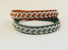 two leather bracelets with braiding on them sitting next to each other in front of a white background