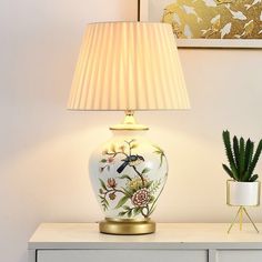 a white lamp sitting on top of a table next to a potted snake plant