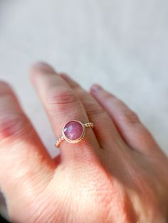 Add a touch of romance to your collection with this enchanting rosecut pink sapphire ring. The gemstone, with its soft, blush-pink hue, catches the light beautifully, revealing subtle facets that glimmer with every movement. Set in a delicate 14k Gold Fill bezel, the sapphire’s gentle color is perfectly complemented by the warm, golden tones of the beaded band, adding a layer of texture and charm. This ring is a perfect blend of feminine elegance and understated luxury, making it an ideal choice Pink Ruby Promise Ring With Rose Cut Diamonds, Pink Ruby Ring With Rose Cut Diamonds For Promise, Pink Ruby Ring With Rose Cut Diamonds, Pink Bezel Set Promise Ring, Rose Gold Ruby Ring With Pink Sapphire, Pink Sapphire Stackable Ring Gift, Rose Gold Pink Sapphire Stackable Rings As Gift, Pink Round Birthstone Ring With Bezel Setting, Rose Gold Stackable Rings With Pink Sapphire As Gift