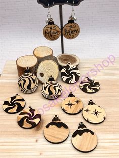 wooden earrings with black and white designs are displayed on a table next to some wood slices