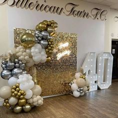 balloons are arranged on the floor in front of a wall with gold and silver letters