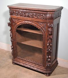 an ornate carved wooden bookcase with glass doors