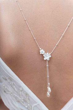 the back of a woman's dress with a flower and pearl necklace on it