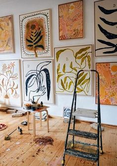 an artist's studio with various paintings on the wall and a ladder in front of them