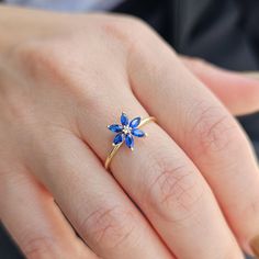 a woman's hand with a blue flower ring on it