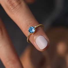 a woman's hand with a ring on her finger and a blue topaz stone