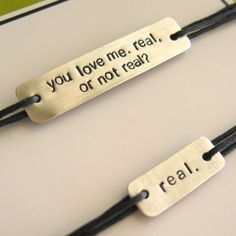 two bracelets that say you love me, real or not real on black cord