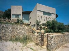 a large house sitting on top of a hill next to a stone wall and trees